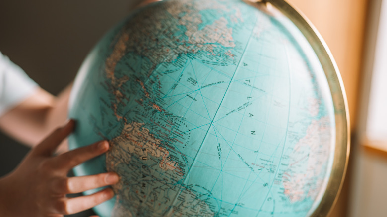 Hands holding globe by a window
